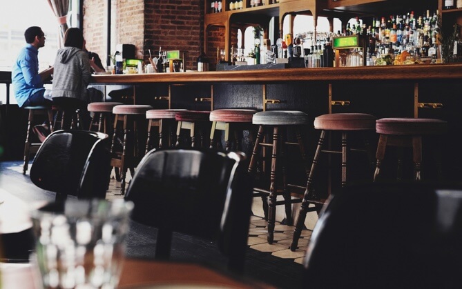 a semi empty drinking bar with empty bar stools